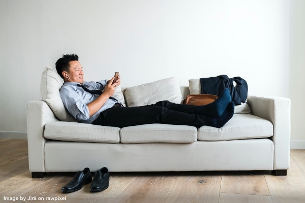 Man in business attire lounging on sofa listening to music representing take the stress out of your next move with Out of Chaos