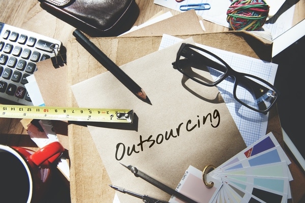 cluttered desk outsourcing your hiring activities written on paper