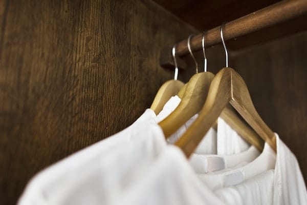 white clothes hanging in wood closet - declutter factor
