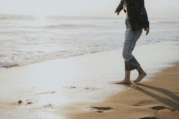 woman walking barefoot on beach get organized enjoy life