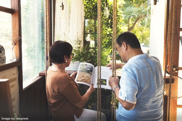 older Asian couple reading a book in their downsized, right-sized home in a new lifestyle