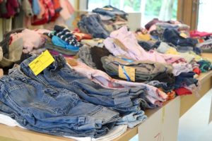 piles of clothing on table after decluttering kids' clothing