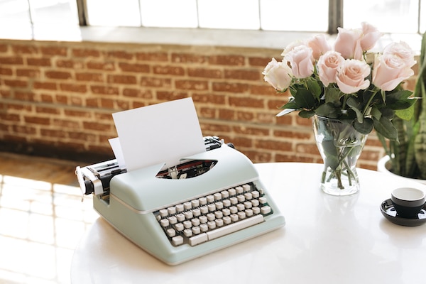 antique vintage retro collectible typewriter on table with vase of flowers