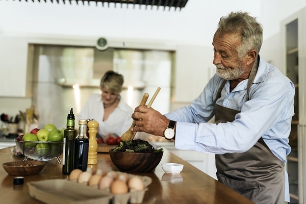 older adult couple preparing meal in tidy kitchen