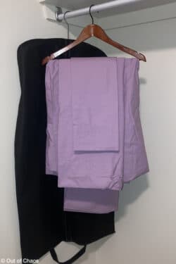 set of purple sheets folded and hung on wooden hanger in closet