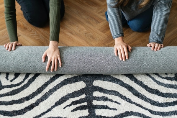 two people rolling up zebra striped carpet for donation representing a friend wants to help