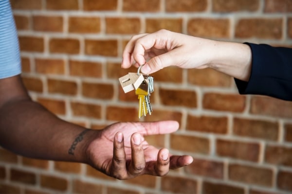 realtor handing keys to new homeowner with tips to make moving in less stressful