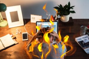 person sitting in front of computer covered in flames representing how to avoid burnout