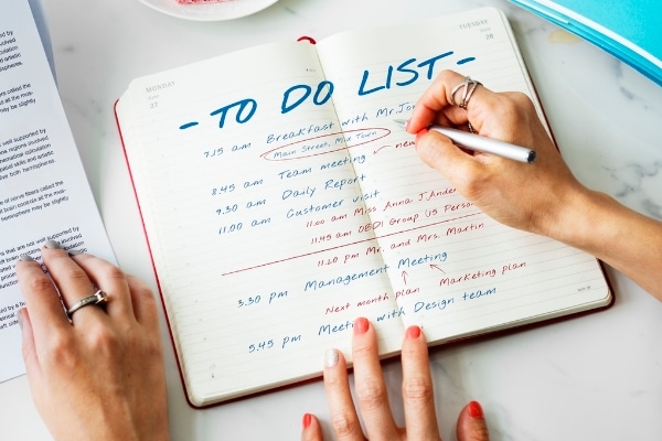 person writing on to do list representing that planning ahead means time is your friend