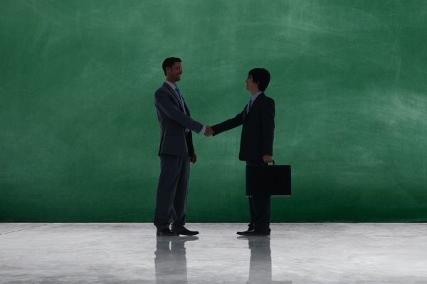 silhouette of expert productivity partners shaking hands against green background