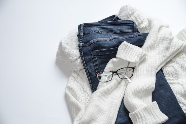 cosy sweater, jeans, eyeglasses on table representing does clothing enhance your productivity