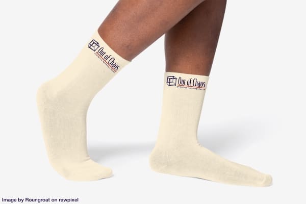 A person's legs and feet wearing socks with Out of Chaos logo on them.