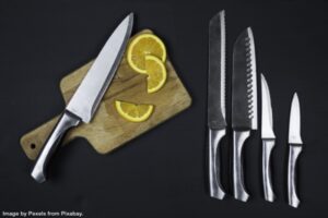 knife on cutting board with lemons beside other knives on counter representing how to organize and store your kitchen knives