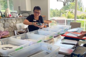 Professional organizer Linda Chu standing at a table organizing school memorabilia into bins