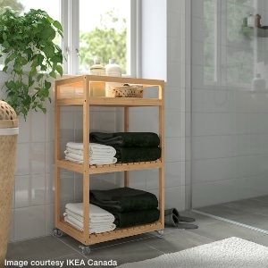 wood bamboo 3-shelf rolling cart used in bathroom to hold towels and personal care supplies