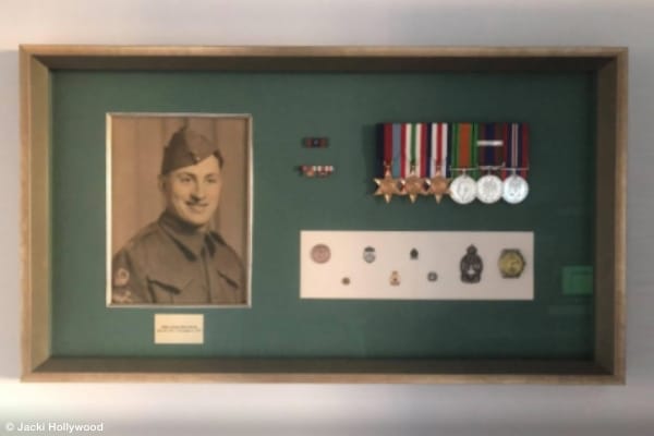 shadow box containing photo of world war two soldier and his medals, ribbons and various military pins and insignia