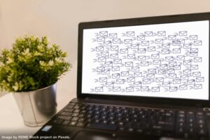 a computer on a desktop with dozens of envelopes on the screen representing email hacks for productivity